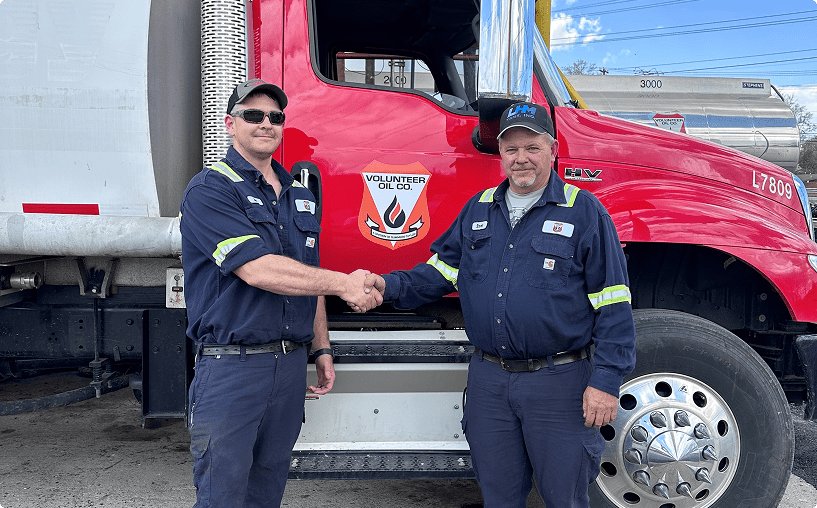 Two men shaking hands by truck.