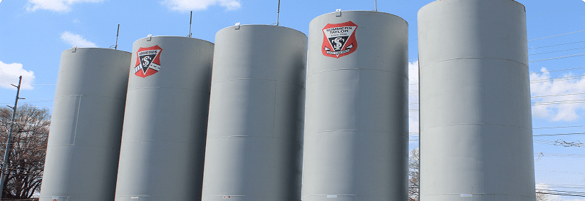 Five large gray industrial storage tanks.